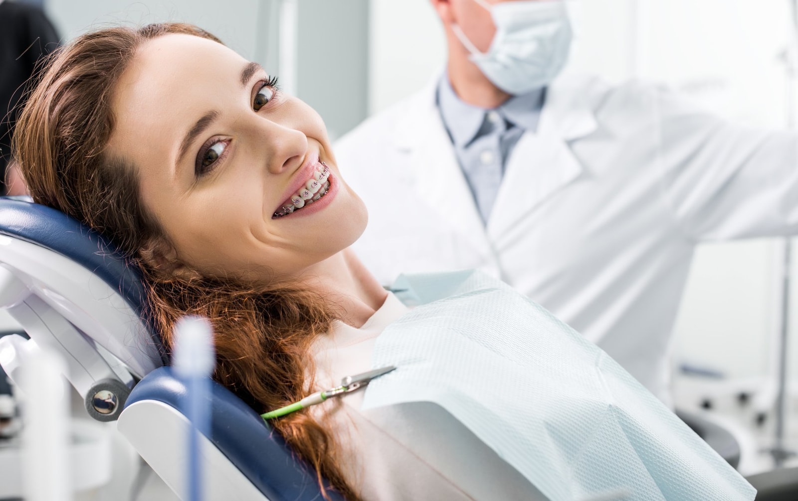 Paziente sorridente con apparecchio ortodontico accanto all'odontoiatra